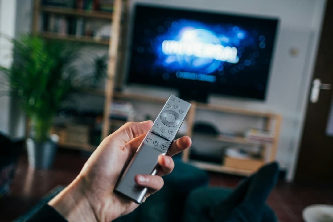 Télécommande pointée vers une Smart TV affichant un menu de streaming
